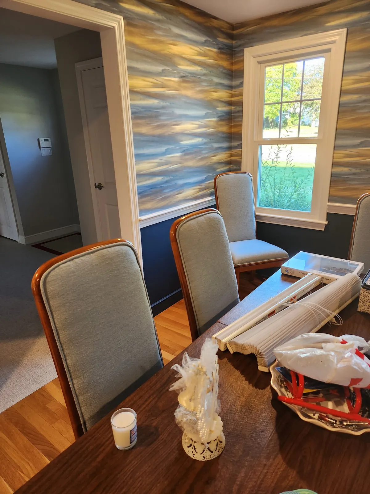 A Victorian parlour with a picture rail, patterned wallpaper above it and a bay window with tall sashes